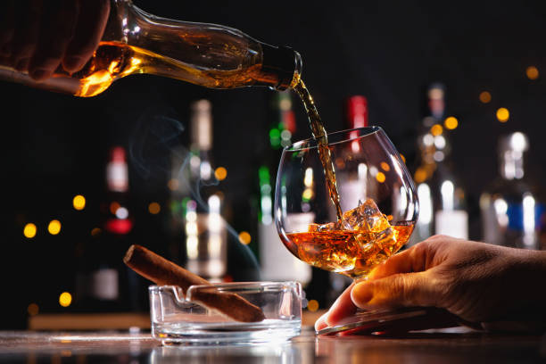 verser un whisky dans un verre sur le comptoir du bar - cigar whisky bar cognac photos et images de collection