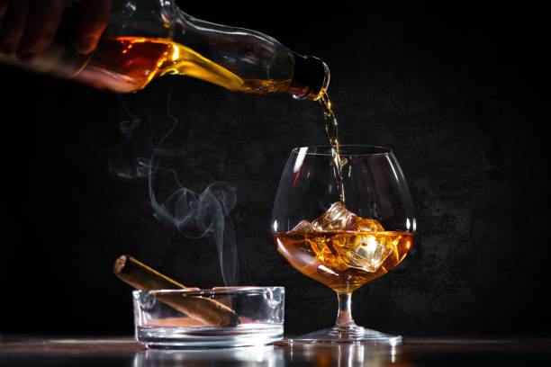 versare un whisky in un bicchiere sul bancone del bar - cigar whisky bar cognac foto e immagini stock