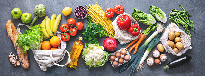 Compras de comestibles. Colocación plana de frutas, verduras, verduras, pan y aceite en bolsas ecológicas, vista superior. photo