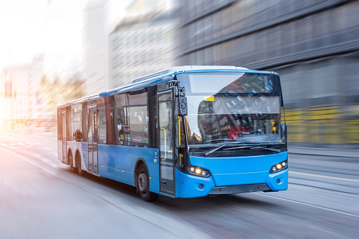 Autobús azul que se mueve en la carretera de la ciudad temprano en la mañana. photo