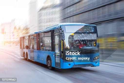 istock Blue bus moving on the road in city in early morning. 1371319562