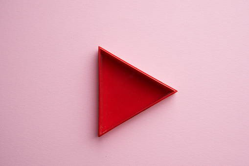 red triangle play button on pink background