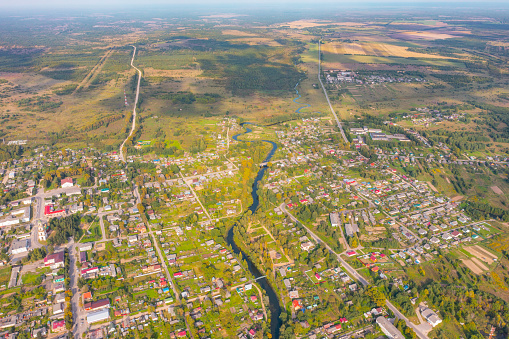 Flying over small provincial town built on a small flat river, aerial view