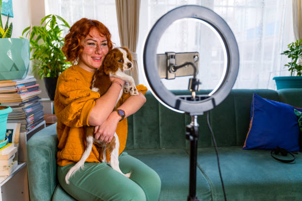 influenceuse excitée faisant un post vlog dans son salon avec son chien - dog pets advice women photos et images de collection