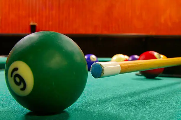 Pool cue and balls shot from low angle, cue tip is sharp
