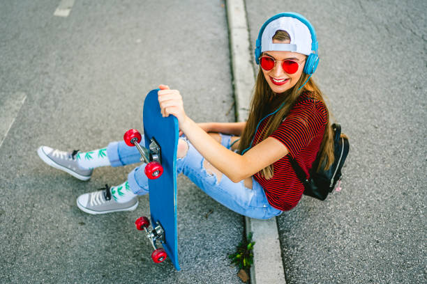 Beautiful smiling young woman sitting with skateboard outdoors