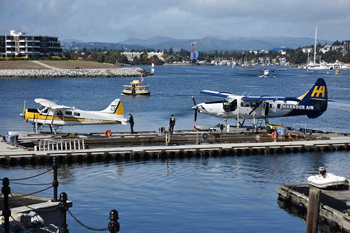 Scene Of People, Water Taxi, Recreational Boat, Building Exterior, Harbour Air Seaplane Preparing To Taking Off During Autumn Season In Victoria British Columbia Canada