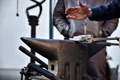 A blacksmith in work. Close up of hand working with a tool on an anvil.