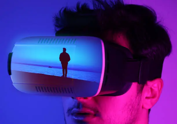 Photo of He is discovering metaverse by using VR glasses under neon lights