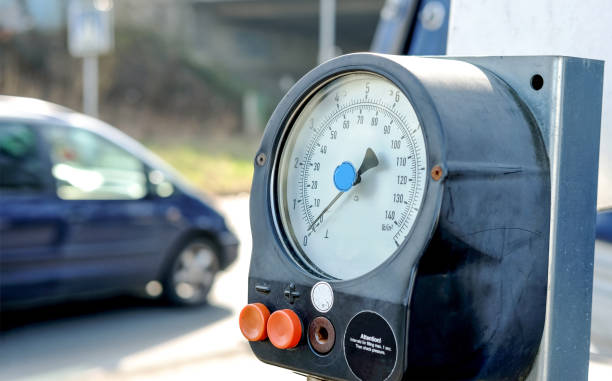 Close-up of a tire pressure gauge at a gas station near a street with a blurred car in the left background Well used tire pressure gauge at a gas station near a street - selective focus and blurred background, copy space pressure sensor stock pictures, royalty-free photos & images