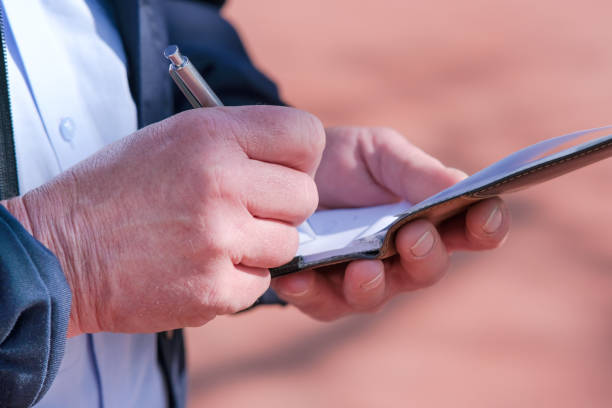 rechts- und sicherheitskonzept: nahaufnahme eines polizeibeamten oder mitarbeiters des ordnungsamtes in uniform beim notizenmachen mit einem stift im block - control clothing image technique image type stock-fotos und bilder