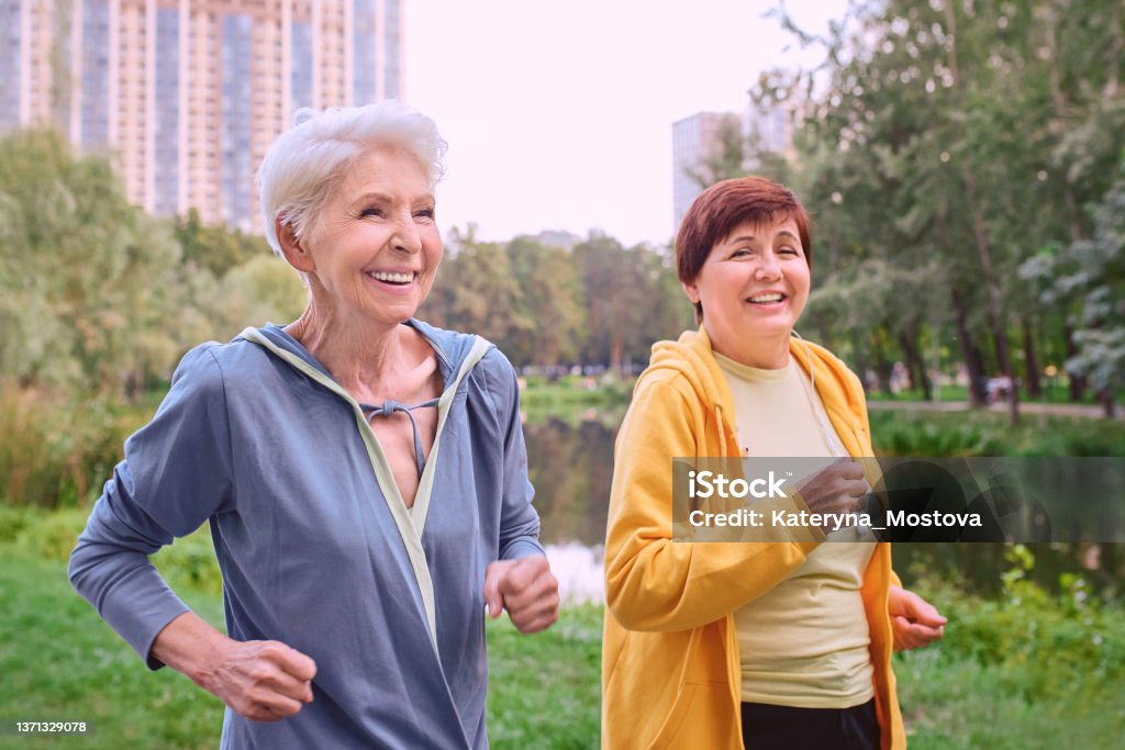 Két érett nő kocog a parkban. egészséges életmód koncepció - Jogdíjmentes Idős témájú stock fotó Két érett nő kocog a parkban. egészséges életmód koncepció - Jogdíjmentes Idős témájú stock fotó