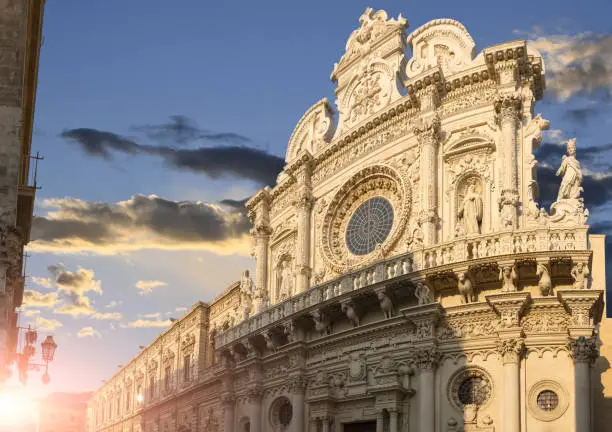 Lecce, Puglia, Italy.August 2021.The church of Santa Croce is the finest example of Lecce baroque.The facade illuminated by the warm light of the evening. Large format panoramic photo.