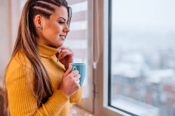 istock Young Woman Looking Out The Window And Drinking Coffee 1371332130