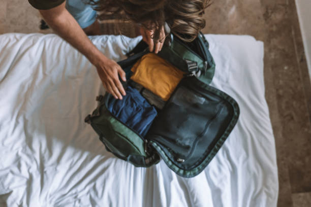Top view of male traveler packing for a trip, puts clothes in a duffel bag stock photo
