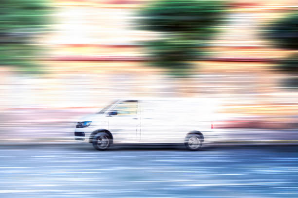 furgone bianco che sfreccia lungo una strada della città. - moving van truck delivery van van foto e immagini stock