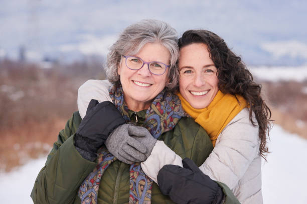 Smiling woman hugging her mom while standing outside in winter