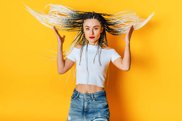 istock Woman with dreadlocks in the air. Yellow studio background. 1371336543