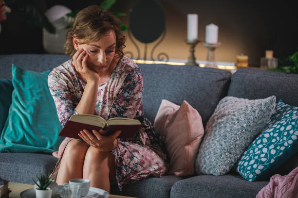 istock Mature woman concentrating on a story while reading a book 1371337875