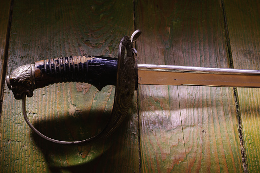 Old rusty sword on wooden green floor.