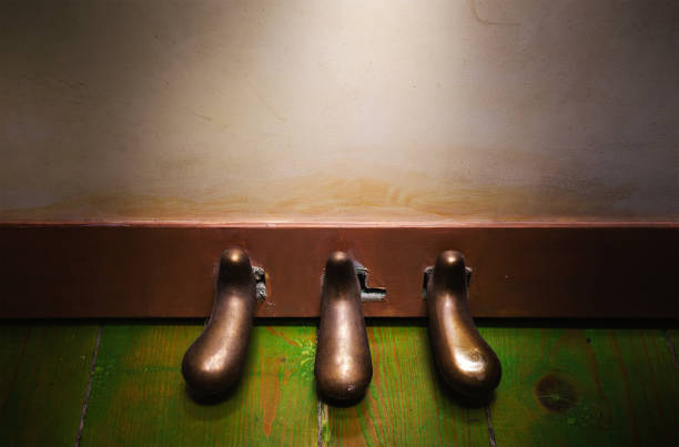 Closeup view on upright piano foot pedals on green wooden floor.
