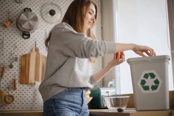istock Young woman peeling orange into  recycling bin, compost bin 1371338700
