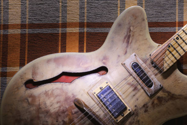 A beautifully crafted electric guitar with a sunburst finish is positioned on a rustic wooden surface. The warm tones and detailed hardware reflect its vintage appeal, highlighting craftsmanship.