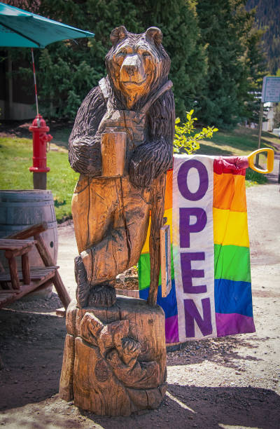 Lounging bear with coffee cup wooden carving and rainbow flag open sign outside outdoor coffee café in tourist town 2021_06_05_9999_Crested Butte CO USA - Lounging bear with coffee cup wooden carving and rainbow flag open sign outside outdoor coffee cafe in tourist town colorado flag art pictures stock pictures, royalty-free photos & images