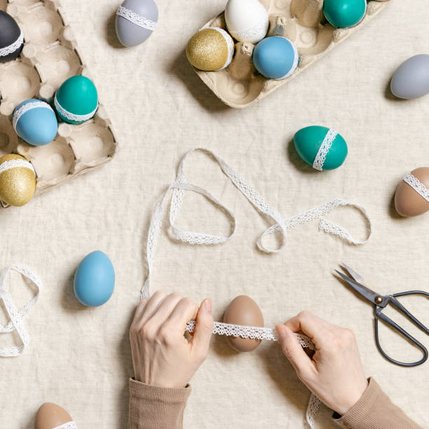 istock Decoration colored Easter eggs, prepare for Happy Easter celebration, woman decorating dyed chicken egg with tape lace on table linen Lifestyle aesthetic photo at home, diy holiday 1371341557