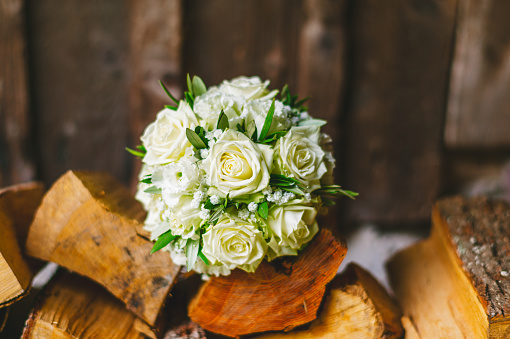 Wedding bouquet with beige roses on a pile of wood