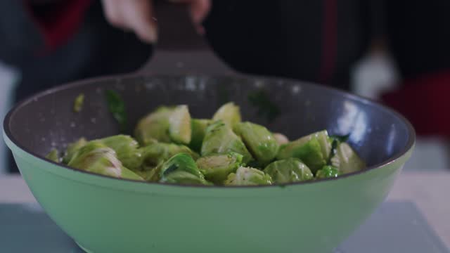 Professional chef sautéing brussels sprouts in oil and spices in a pan