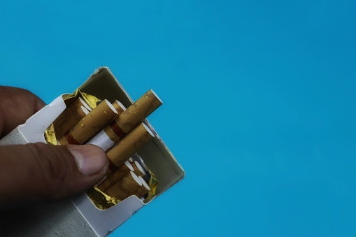 lighter and cigarette almost out of the pack on a blue background
