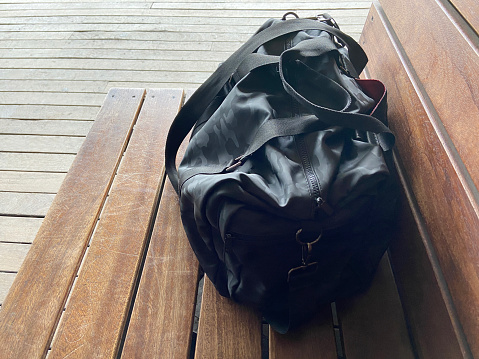 Sport and travel bag on the wooden seat at the outdoor