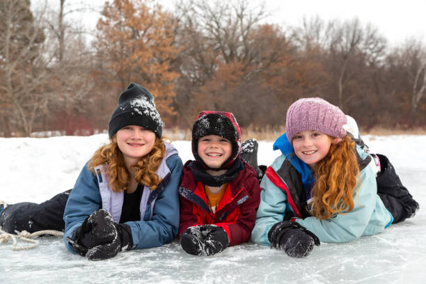Three Siblings On Ice Smiling At Camera stock photo