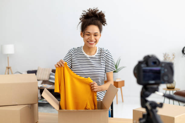 istock African American female vlogger freelancer using camera to recording video content makes review of products ordered online Woman owner of online clothing store shoots an advertisement for her product 1371356782