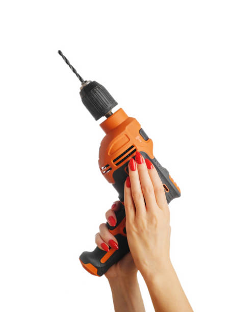 Female hand with a red manicure and an power drill. Woman's hands with a red manicure and an power drill on an isolated white background. holding drill stock pictures, royalty-free photos & images