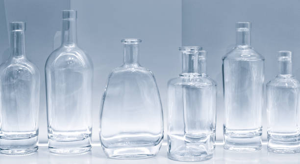 istock Empty glass bottles in a row on a shelf in blue tone, isolated on white background 1371359592