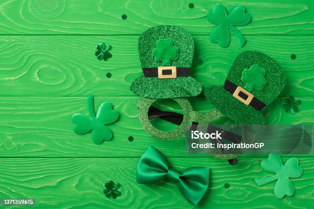 Top View Photo Of St Patricks Day Decorations Shamrocks Trefoil Shaped Confetti Funny Outfit Hat Shaped Party Glasses And Green Bowtie On Isolated Textured Green Wooden Desk Background Stock Photo - Download Image Now