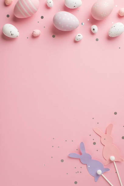 istock Top view vertical photo of easter decorations glowing confetti easter bunny silhouettes lilac pink and white easter eggs on isolated pastel pink background with copyspace 1371359770