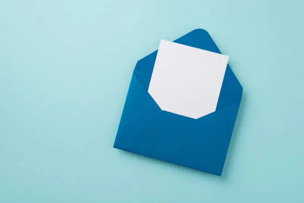 Photo of Top view photo of open blue envelope with paper sheet on isolated pastel blue background with empty space