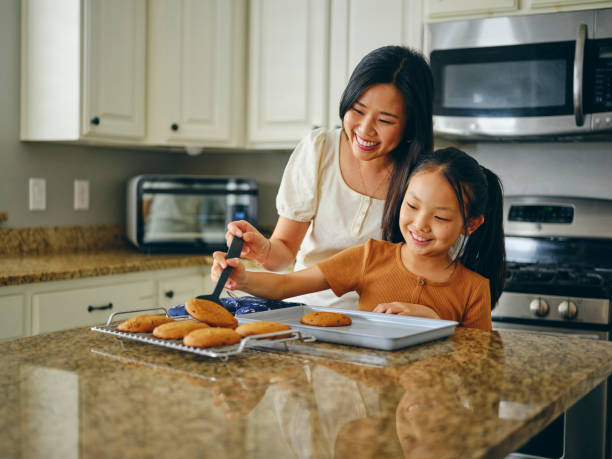 Mom and Children Baking Cookies A mom and her children with freshly baked cookies in a home kitchen. asian kid cooking stock pictures, royalty-free photos & images