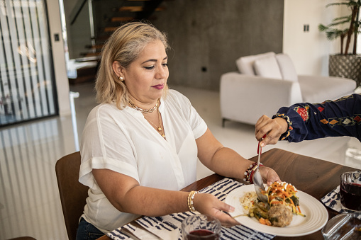 Mature Latin woman being served a traditional Mexican food at home