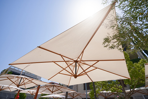 A large umbrella protects from the sun in a street cafe.