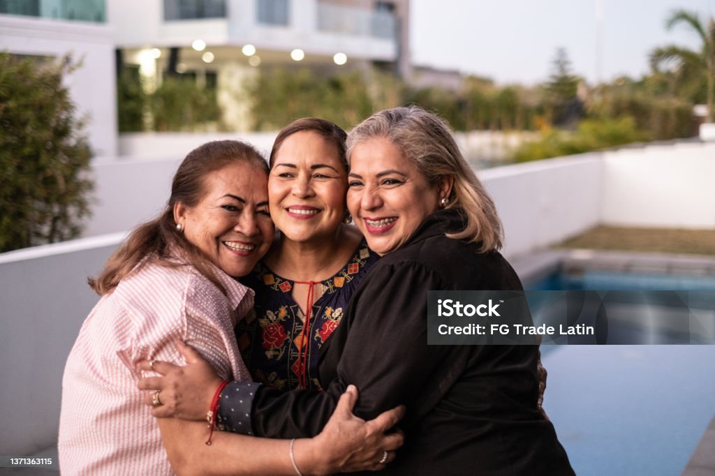 Female Latin friends hugging each other and laughing at home Latin American and Hispanic Ethnicity Stock Photo