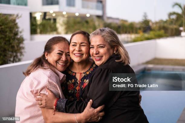 Female Latin Friends Hugging Each Other And Laughing At Home Stock Photo - Download Image Now