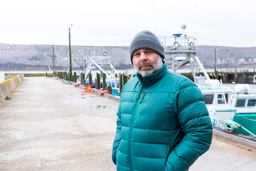 A commercial fisherman in a fishing harbor in front of trawlers