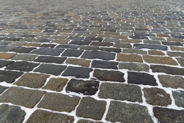 Stone pavement in winter. Old paved road. Snow between stones.  Ancient pavement lined with blocks