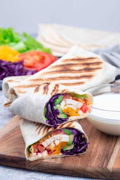 istock Chicken wraps with red cabbage, avocado, tomato, lettuce and cheddar cheese, on wooden board 1371369954
