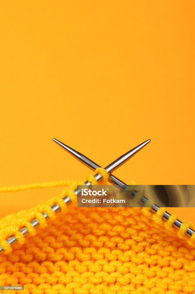 Knitting with needles on colored paper backdrop. Ball Of Wool Stock Photo