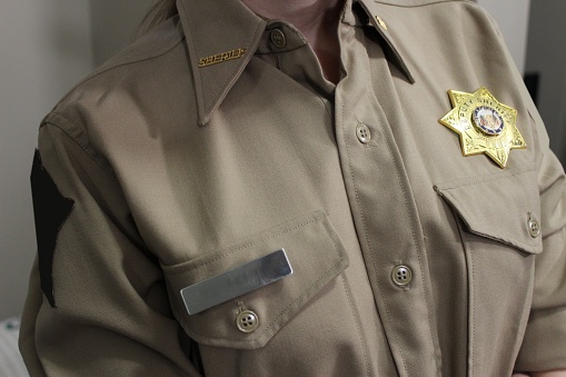 Female deputy Sheriff in western clothing close ups of badge, gun belt